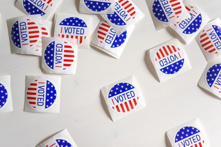 White stickers reading "I Voted" scattered on a white background